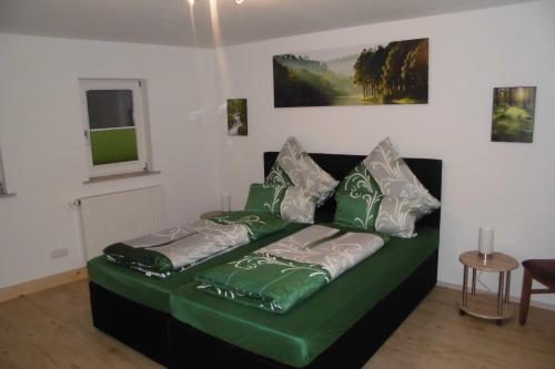 a couch with green and white pillows in a living room at Gasthaus Beyersdorfer in Rieth