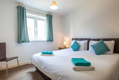 a bedroom with a large white bed with blue pillows at Apartment D204 in Northampton