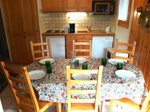 une cuisine avec une table, des chaises et un tissu de table dans l'établissement HAMEAU DES HUSKIES, à Saint-Gervais-les-Bains