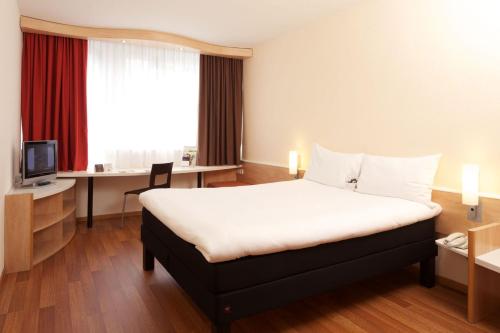 a hotel room with a bed and a desk at Ibis Budapest City in Budapest