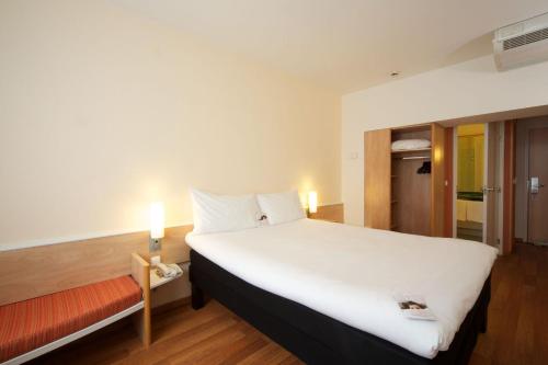 una habitación de hotel con una gran cama blanca y una ventana en Ibis Budapest City en Budapest