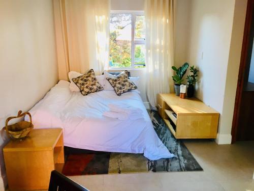 Johannesburg的住宿－Kilkenny Cottages 2 bedroom unit，卧室配有带枕头的床铺和窗户。