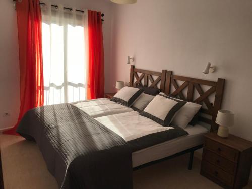 a bedroom with a large bed with red curtains and a window at Apartamento Atico Guanchita in Tazacorte