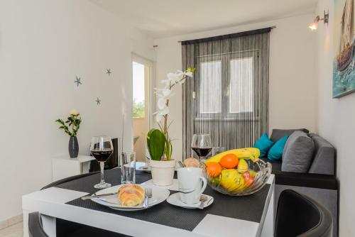 a table with two glasses of wine and a bowl of fruit at Apartment- SUNCE in Kaštela