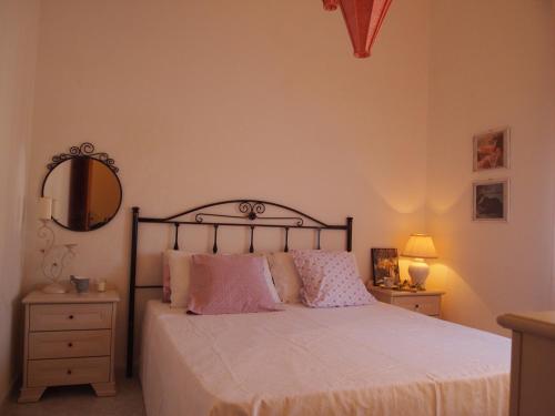 a bedroom with a bed with pink pillows and a mirror at Terre del Faro in Scanzano