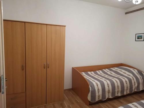 a bedroom with a bed and a wooden cabinet at Apartmani Spomenka in Seline