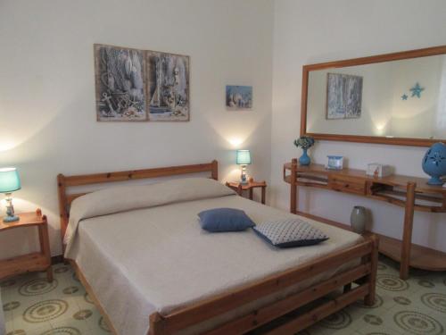 1 dormitorio con 1 cama con 2 lámparas y espejo en Villa Oltremare, en Punta Prosciutto