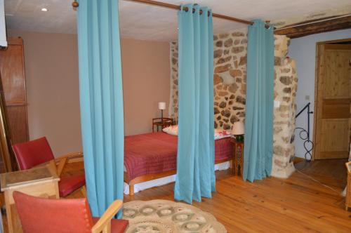 um quarto com uma cama com cortinas azuis em Les pentes du chateau de Retourtour em Lamastre