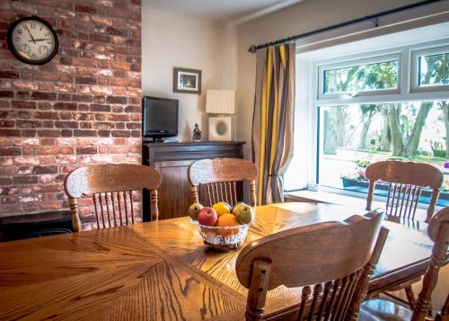 a dining room table with a bowl of fruit on it at Mallard Cottage in Whitehead