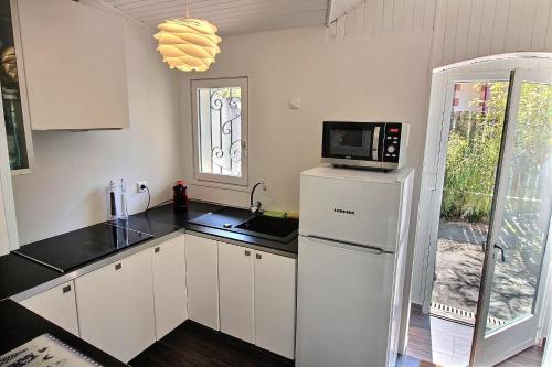 La cuisine est équipée d'un réfrigérateur blanc et d'un four micro-ondes. dans l'établissement La Favorite, à Arcachon