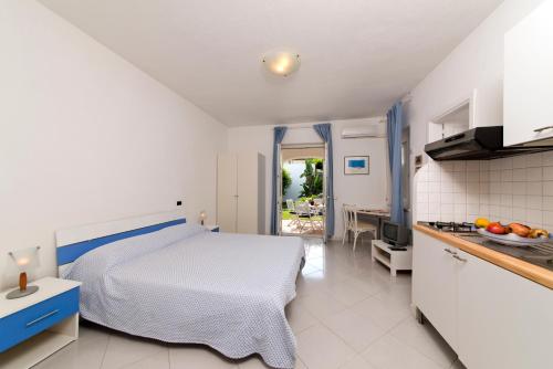 ein weißes Schlafzimmer mit einem Bett und einer Küche in der Unterkunft Casa Agave in Ischia