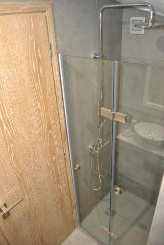 a shower with a glass door next to a sink at Petras Gi - Stone Houses in Stoupa