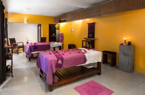 a room with three beds with pink and purple sheets at Tangerine Beach Hotel in Kalutara