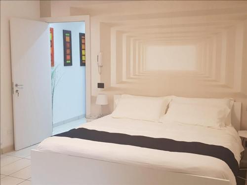 un letto bianco in una stanza con porta di Tamb&B2 a Bologna