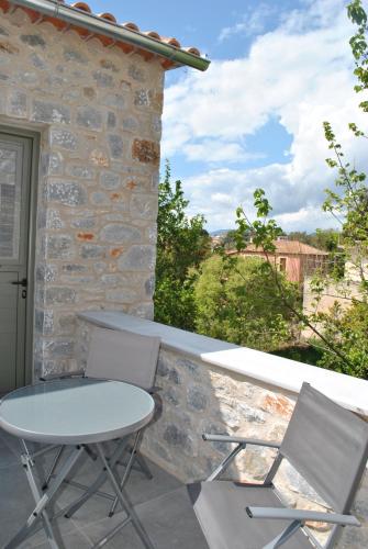 a table and two chairs sitting on a balcony at Petras Gi - Stone Houses in Stoupa