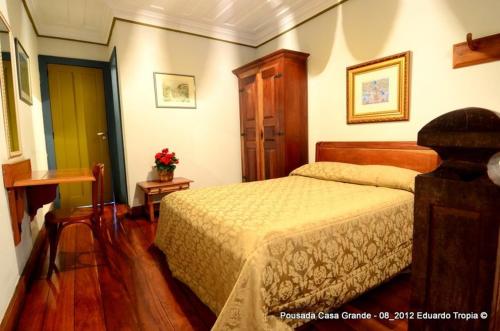 a bedroom with a bed and a table with flowers at Hotel Pousada Casa Grande in Ouro Preto