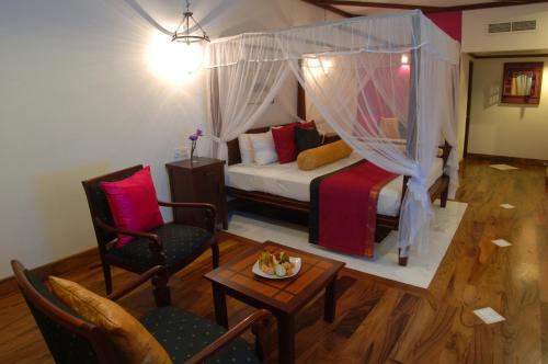a bedroom with a bed and two chairs and a table at Tangerine Beach Hotel in Kalutara