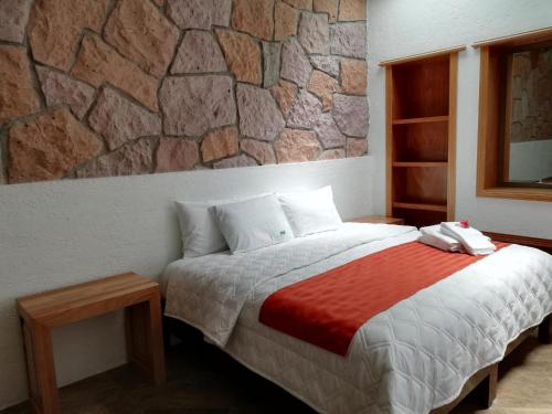 a bedroom with a bed and a stone wall at Hacienda Maxdá in Santiaguito Maxdá