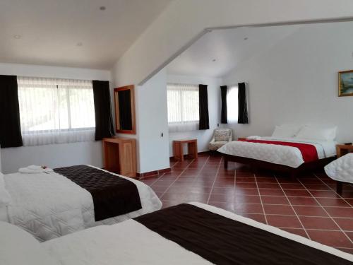 a bedroom with three beds and a red tile floor at Hacienda Maxdá in Santiaguito Maxdá