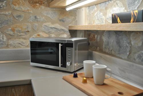 a microwave sitting on top of a counter with two cups at Petras Gi - Stone Houses in Stoupa