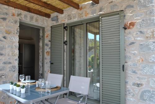 a stone walled patio with a table and chairs at Petras Gi - Stone Houses in Stoupa