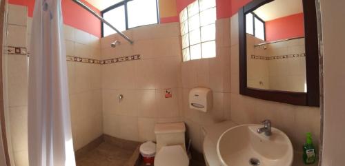 a bathroom with a sink and a toilet and a mirror at Hostal Duncan in Puerto Ayora