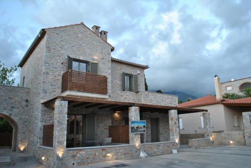 a house with a balcony on the side of it at Petras Gi - Stone Houses in Stoupa