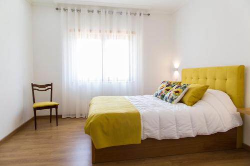 a bedroom with a bed with a yellow headboard and a window at Quinta Teoria - Teoria Guest House in Sabrosa