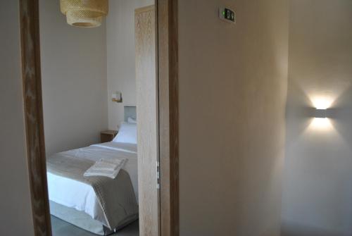 a bedroom with a bed and a door with a light at Petras Gi - Stone Houses in Stoupa