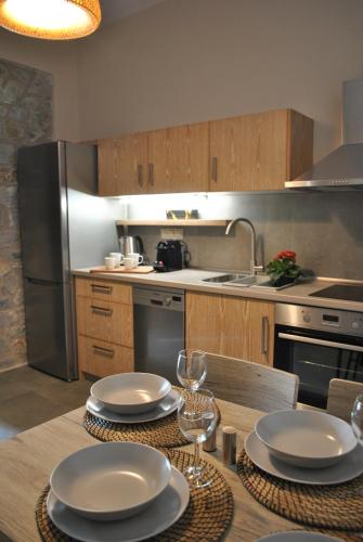 a kitchen with a table with plates and wine glasses at Petras Gi - Stone Houses in Stoupa