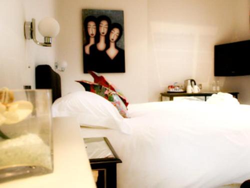 a bedroom with a white bed and a picture of two girls at Hartnoll Hotel & Spa in Tiverton