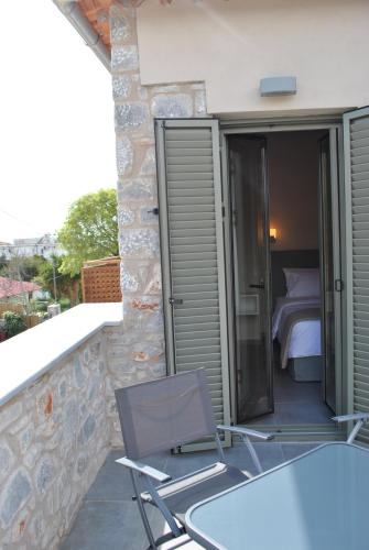 a room with a bed and a table and chairs on a balcony at Petras Gi - Stone Houses in Stoupa