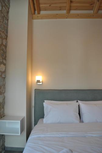 a bed with white pillows and a green headboard at Petras Gi - Stone Houses in Stoupa