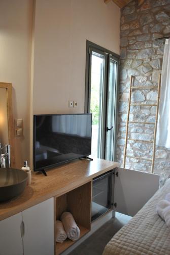 a living room with a tv and a counter with a television at Petras Gi - Stone Houses in Stoupa