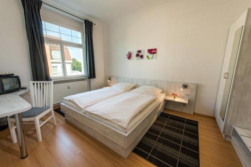 a bedroom with a bed and a desk and a window at City Hotel in Eisenach