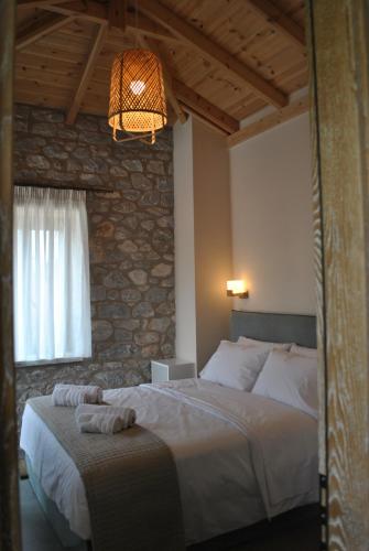 1 dormitorio con cama y pared de piedra en Petras Gi - Stone Houses, en Stoupa