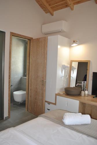 a bathroom with a sink and a toilet and a mirror at Petras Gi - Stone Houses in Stoupa