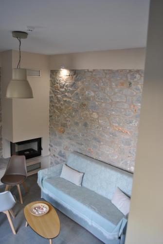 a living room with a blue couch and a stone wall at Petras Gi - Stone Houses in Stoupa