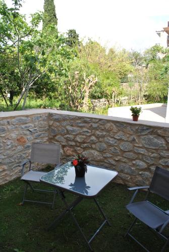 a table and two chairs and a stone wall at Petras Gi - Stone Houses in Stoupa