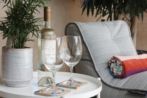 a table with two wine glasses and a bottle of wine at Tomfoolery Winemaker's Cottage Barossa Valley in Lights Pass