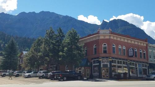 a red brick building with cars parked in a parking lot at Hotel Ouray - for 12 years old and over in Ouray