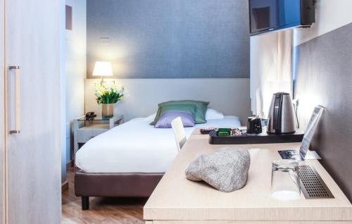 a hotel room with a bed and a desk with a laptop at Hotel Oro Blu in Milan