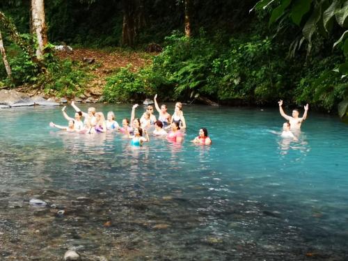 a group of people swimming in the water at Hotel SueñoReal RioCeleste in Rio Celeste