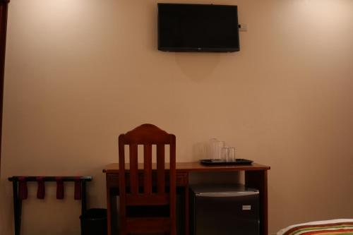 a desk with a chair and a television on a wall at Hotel SueñoReal RioCeleste in Rio Celeste