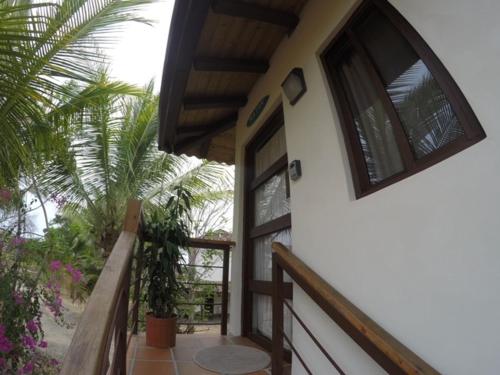 a balcony of a house with a door and a palm tree at Cabañas La Casa de Pucha in Pedasí Town