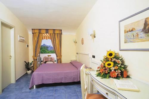 a hotel room with a bed and a table with flowers at Hotel San Giovanni Terme in Ischia