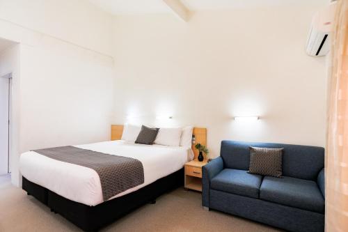 a bedroom with a bed and a blue chair at Parkhaven in Nowra