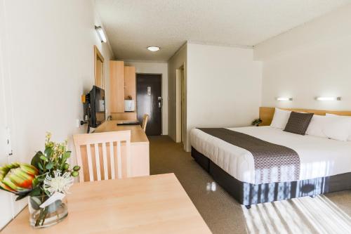 a bedroom with a bed and a table and a kitchen at Parkhaven in Nowra