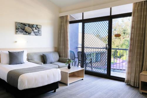 1 dormitorio con cama, sofá y balcón en Parkhaven, en Nowra
