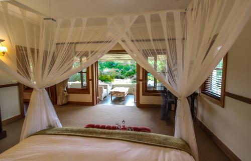 1 dormitorio con 1 cama con cortinas en una habitación en Dune Ridge Country House, en St Francis Bay